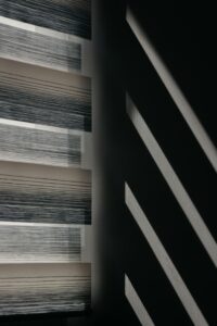 Modern window blinds create striking shadows on a wall for an abstract visual effect.